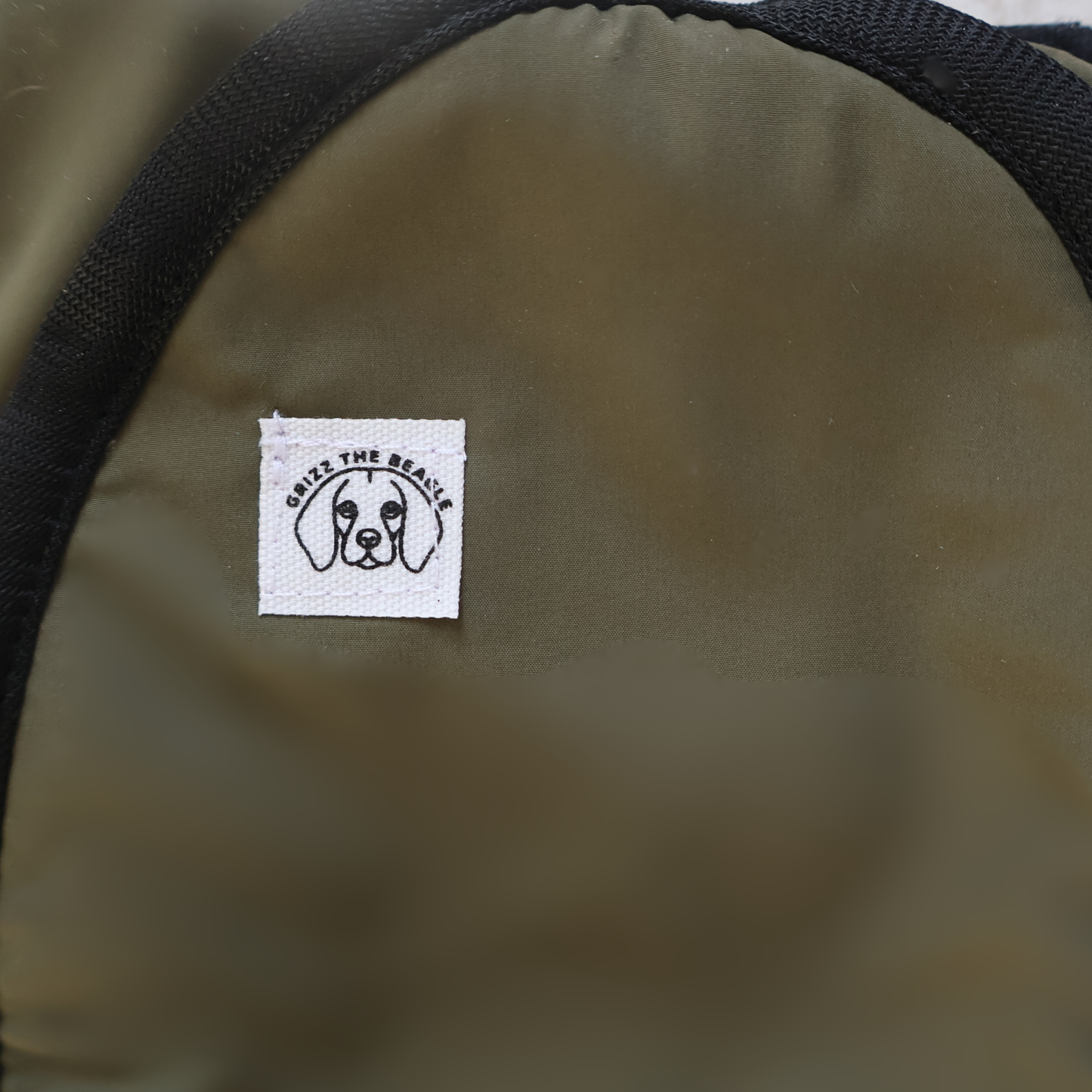 Close-up of a forest green ear muffs featuring a dog illustration and text.
