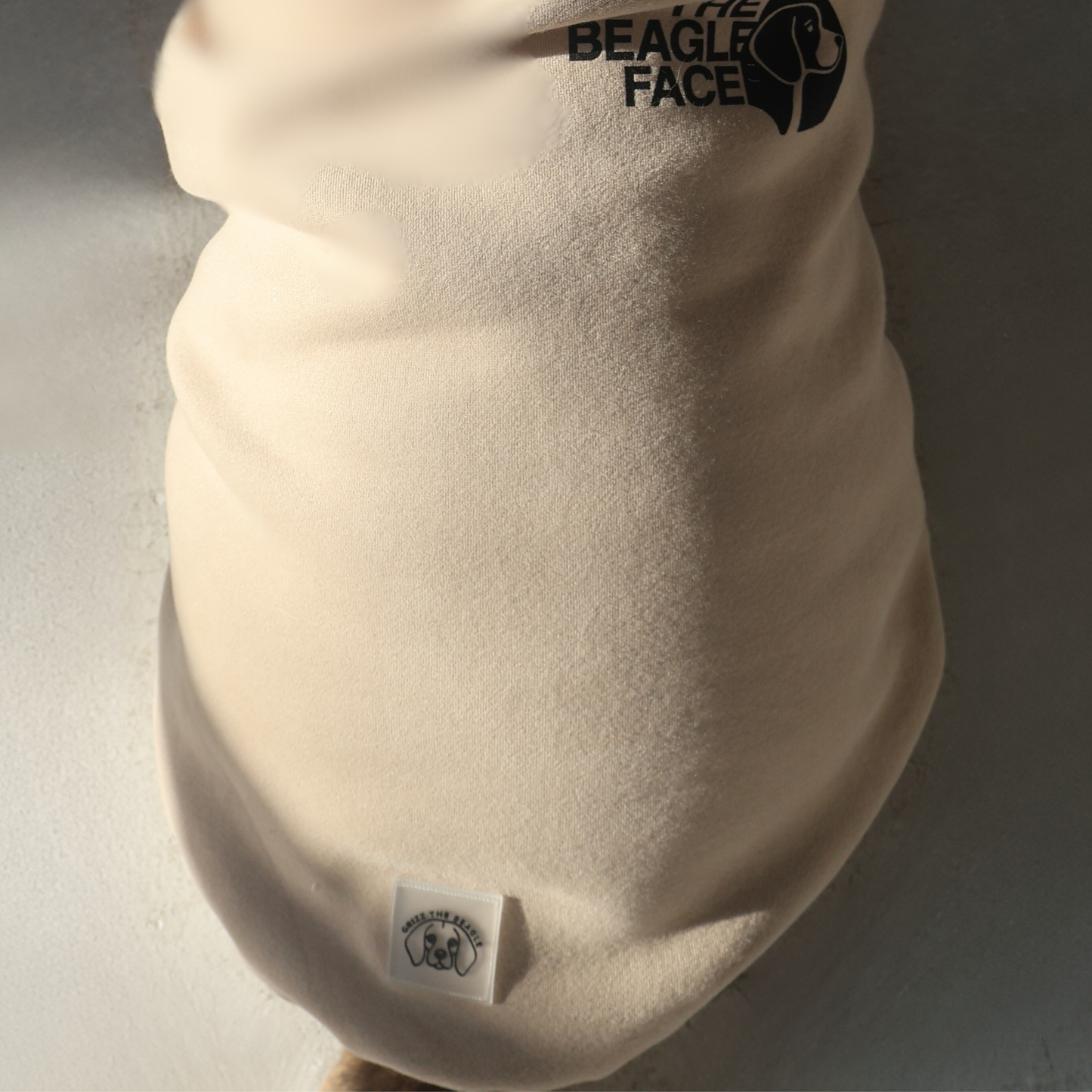Beige fleece dog sweater with 'The Beagle Face' logo on a neutral background