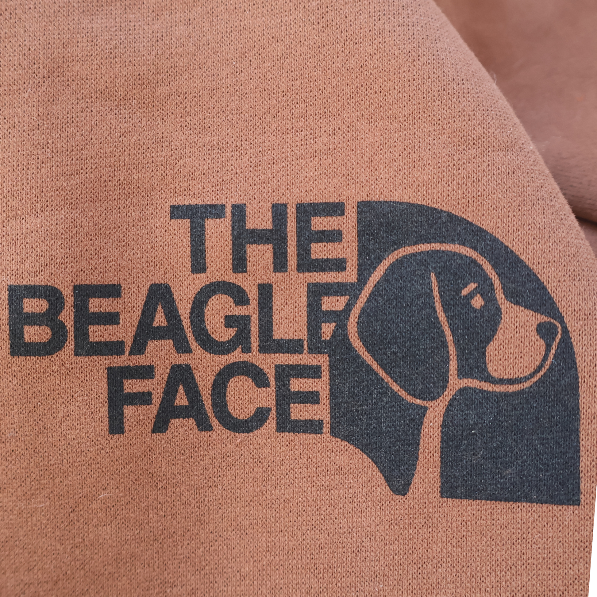 Text 'THE BEAGLE FACE' with a beagle outline on brown fabric.