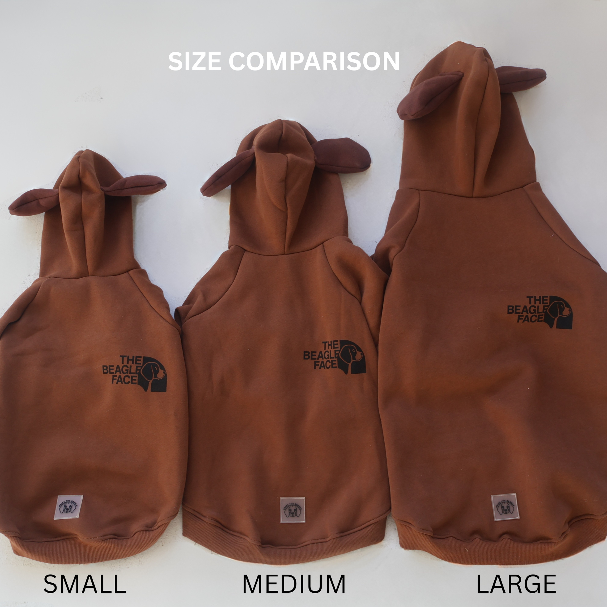 Three brown dog hoodies with 'The Beagle Face' logo on a white background