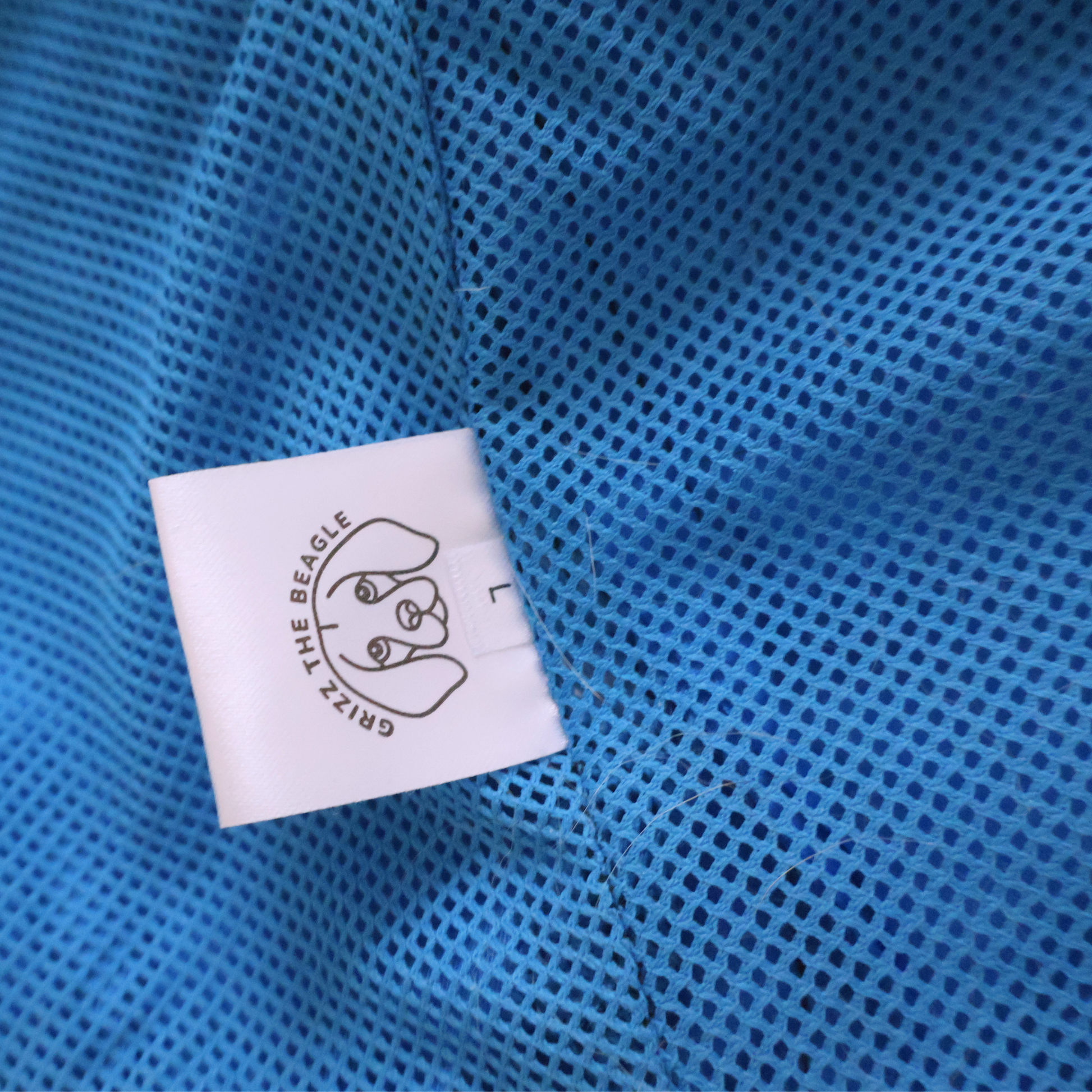 Close-up of a blue textured mesh fabric with a white label featuring a logo and text.